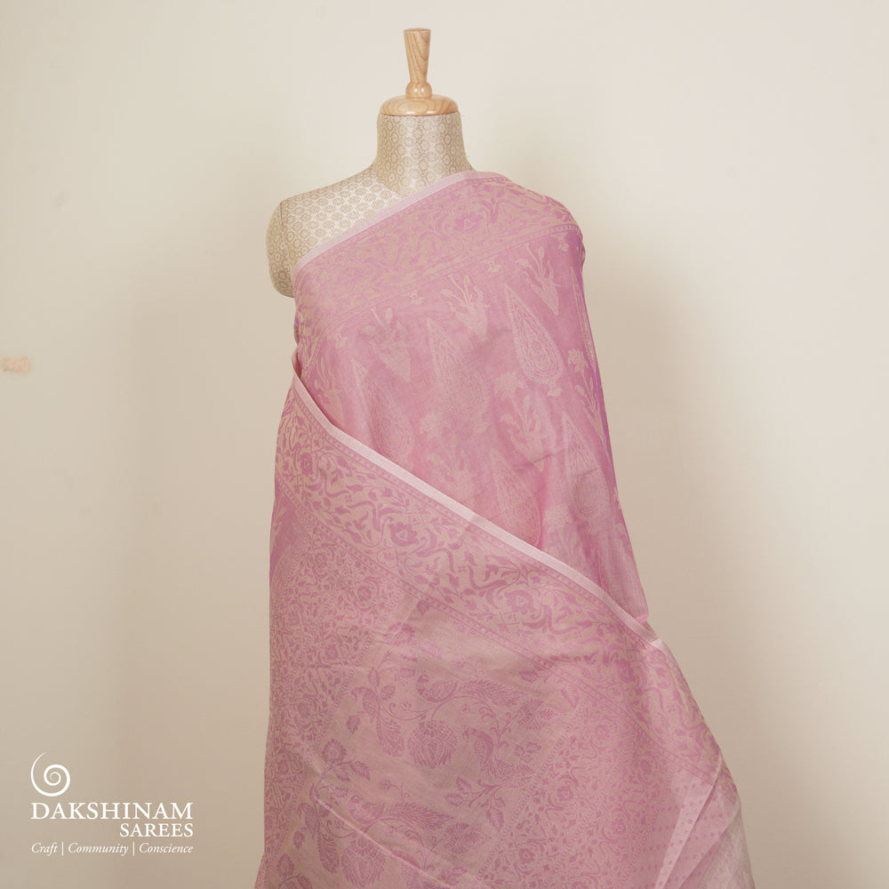 Pink South cotton saree with plant and paisley motifs across the body, floral border and peacock motif pallu, matching blouse with diamond butta design.