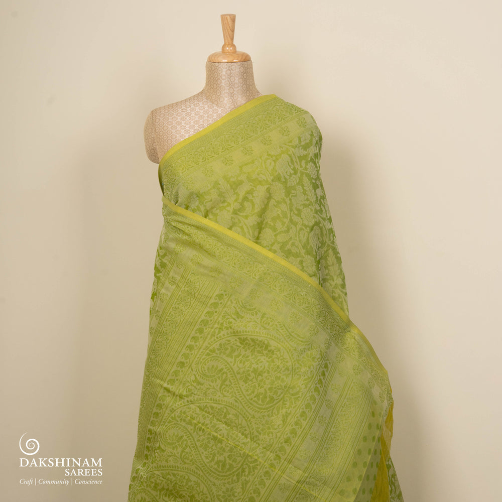 Lime green South cotton saree with floral body featuring peacock, horse, elephant, deer and tiger motifs, traditional border and paisley pallu, matching blouse with dot design.