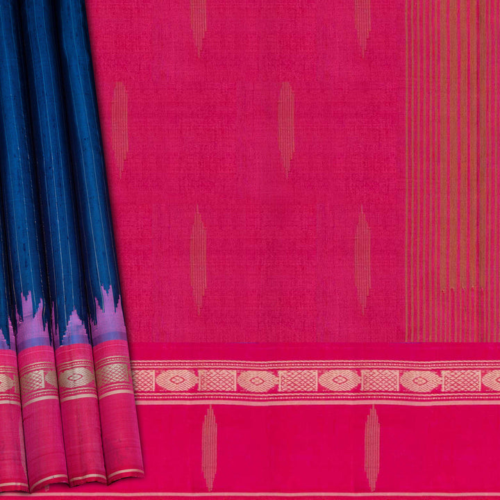 Blue Gadwal silk saree with raw silk finish body, silver stripe detailing, pink border with chakram and thazampoo motifs, pink blouse.