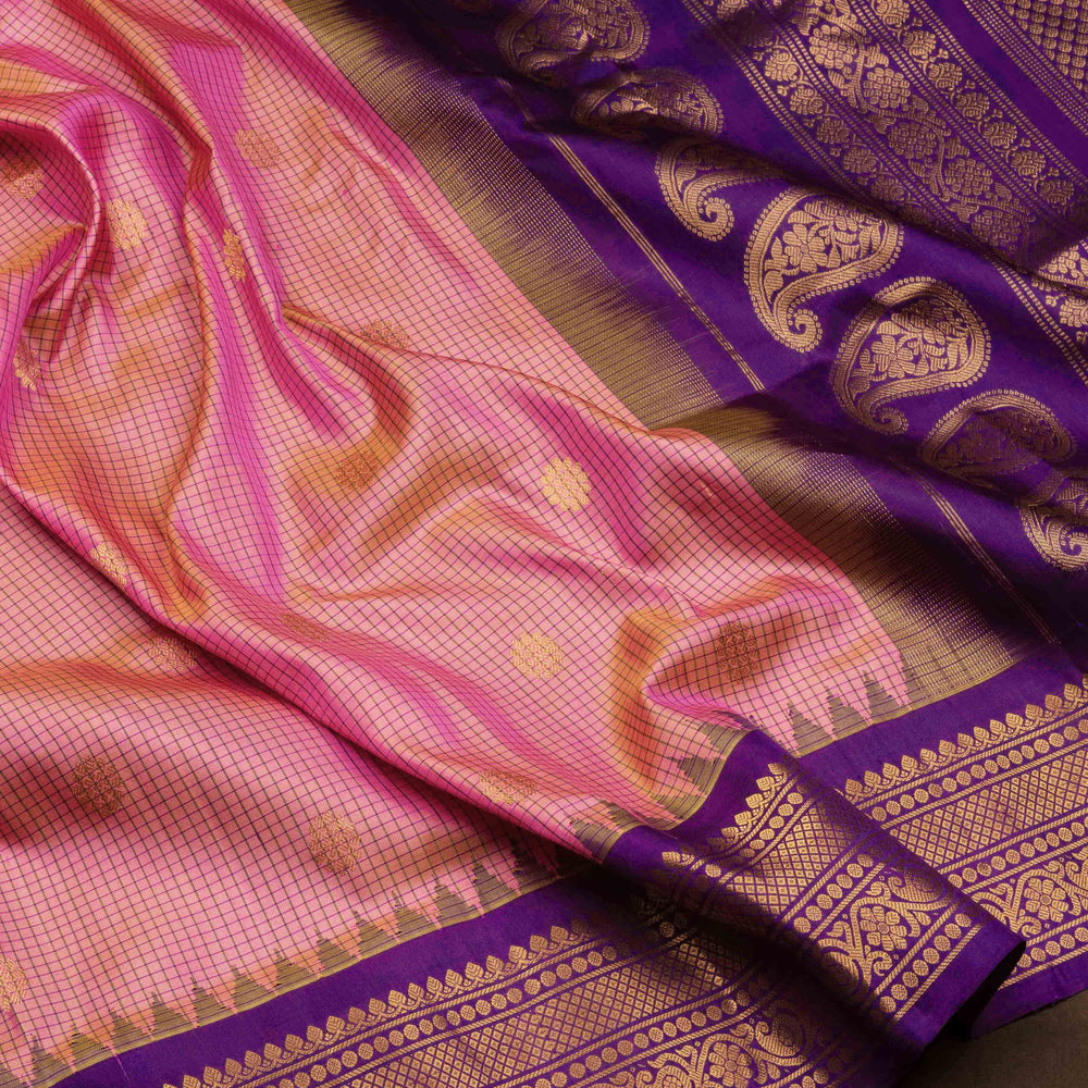 Dual tone pink and orange Gadwal silk saree with checkered body, purple zari border with rudraksh and temple motifs, plain purple blouse.