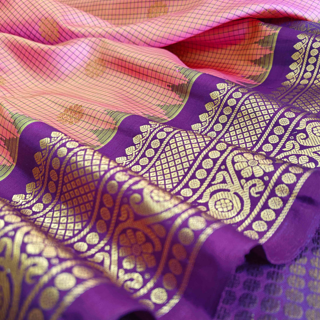 Dual tone pink and orange Gadwal silk saree with checkered body, purple zari border with rudraksh and temple motifs, plain purple blouse.