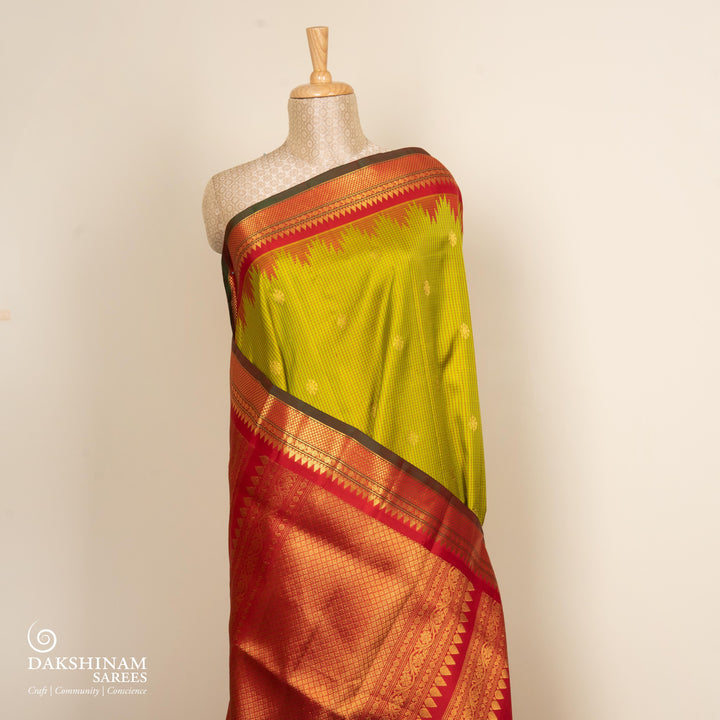 Lime green Gadwal silk saree with red check lines and small butta body, red zari border with rudraksh and mango motifs, plain red blouse.