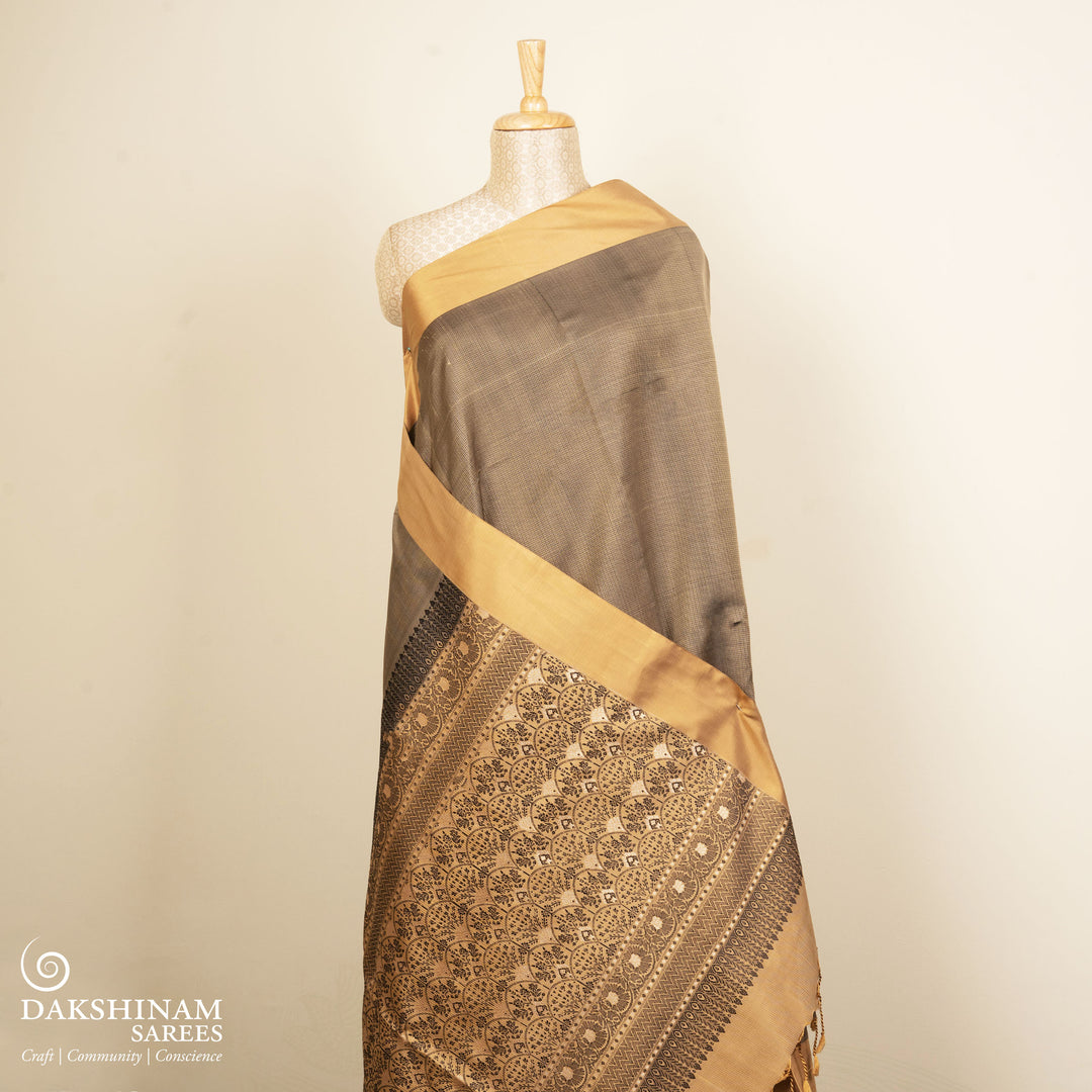 Beige soft silk saree with self-textured body, plain border and beige pallu with floral vine, lotus and chevron motifs in black and gold zari, paired with black blouse.