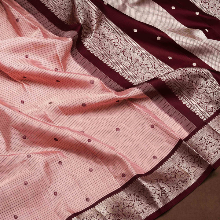 Peach handwoven Kanjivaram silk saree with horizontal stripes and chakram buttas, maroon border with parrot and floral motifs, and matching maroon blouse.