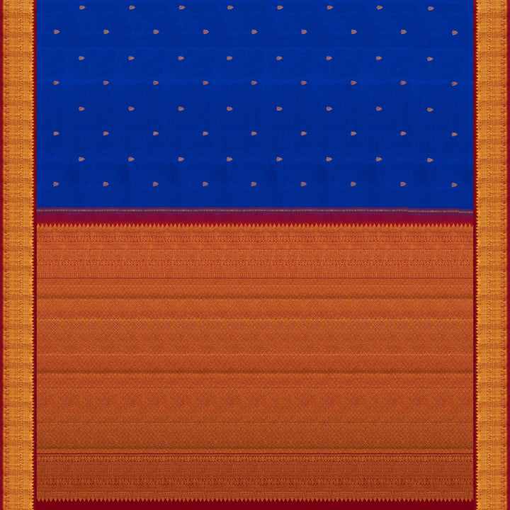 Blue handwoven Kanjivaram silk saree with gold buttas, red border with chevron and floral designs, and matching pallu, paired with plain red blouse.