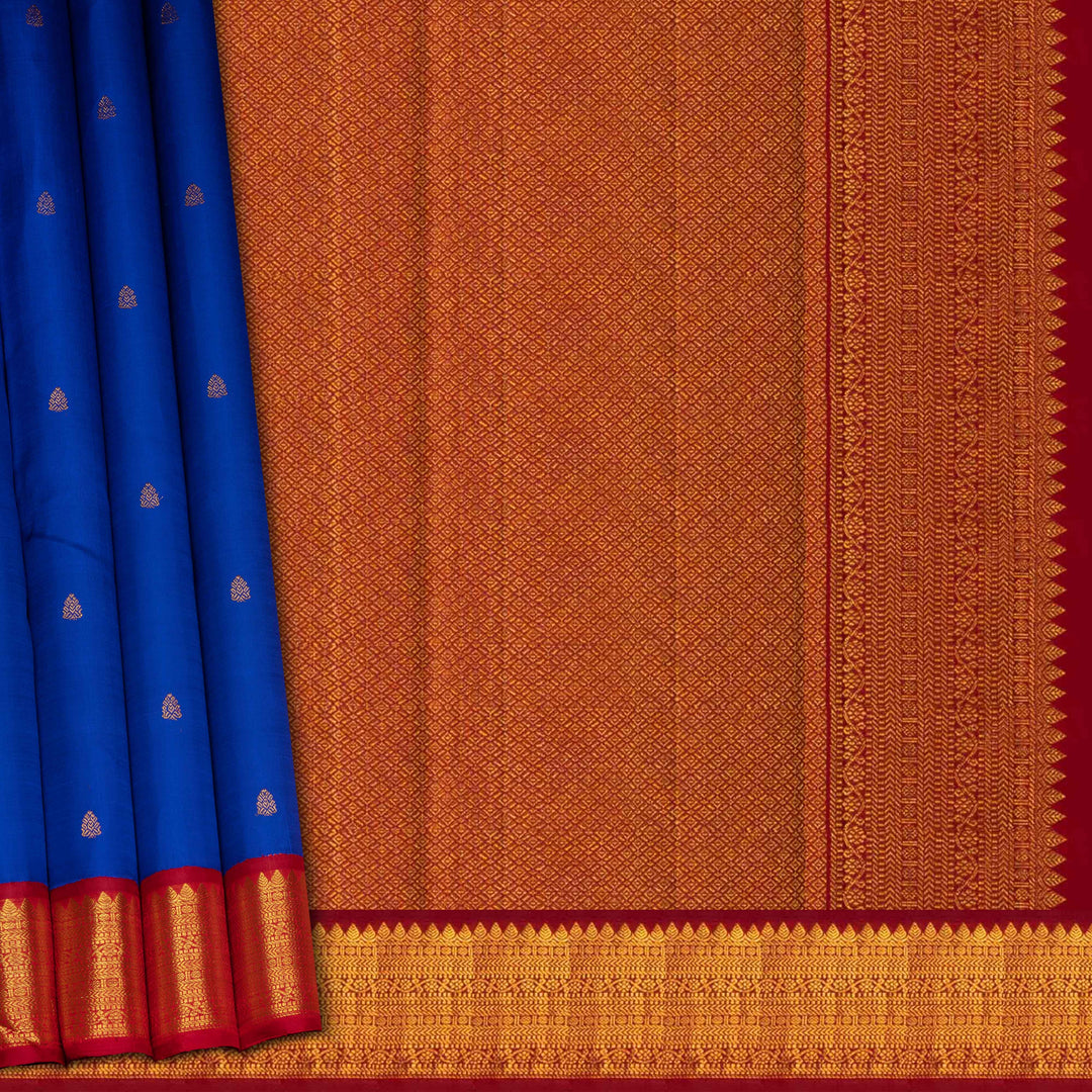 Blue handwoven Kanjivaram silk saree with gold buttas, red border with chevron and floral designs, and matching pallu, paired with plain red blouse.