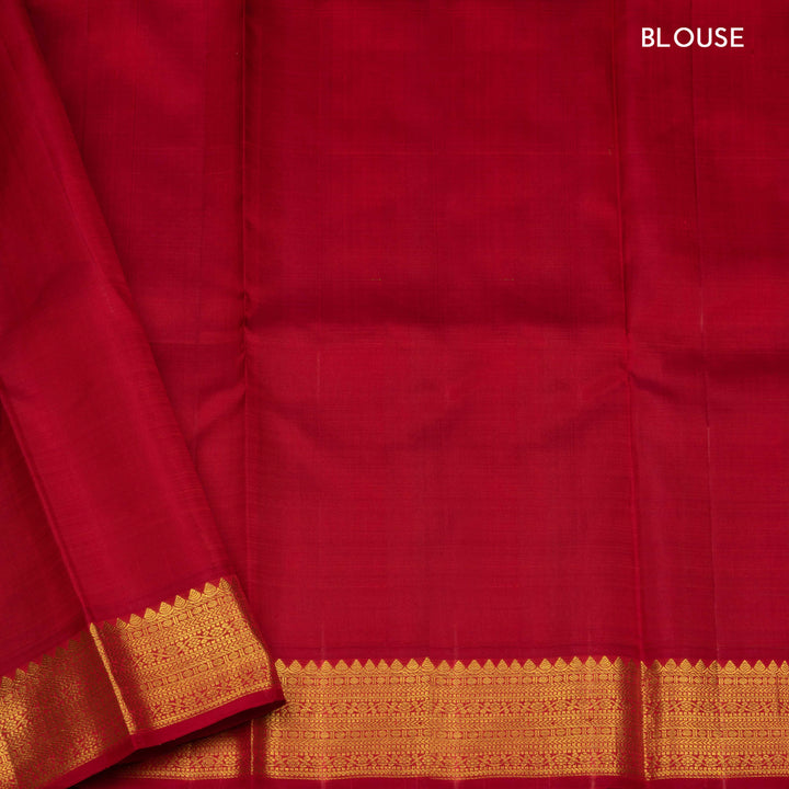 Blue handwoven Kanjivaram silk saree with gold buttas, red border with chevron and floral designs, and matching pallu, paired with plain red blouse.