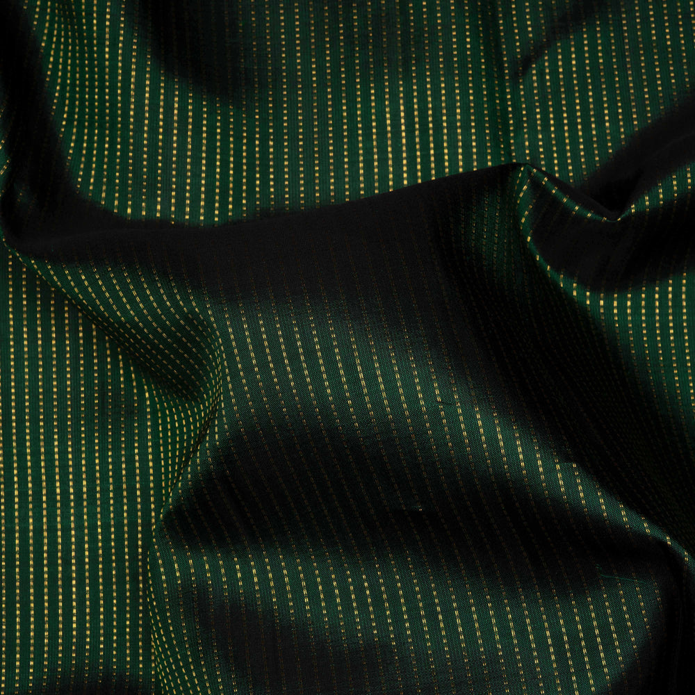 Green handwoven Kanjivaram silk saree with vertical gold dash buttas, rettapet border, and peach-pink dual tone pallu with zari motifs, paired with peach blouse.