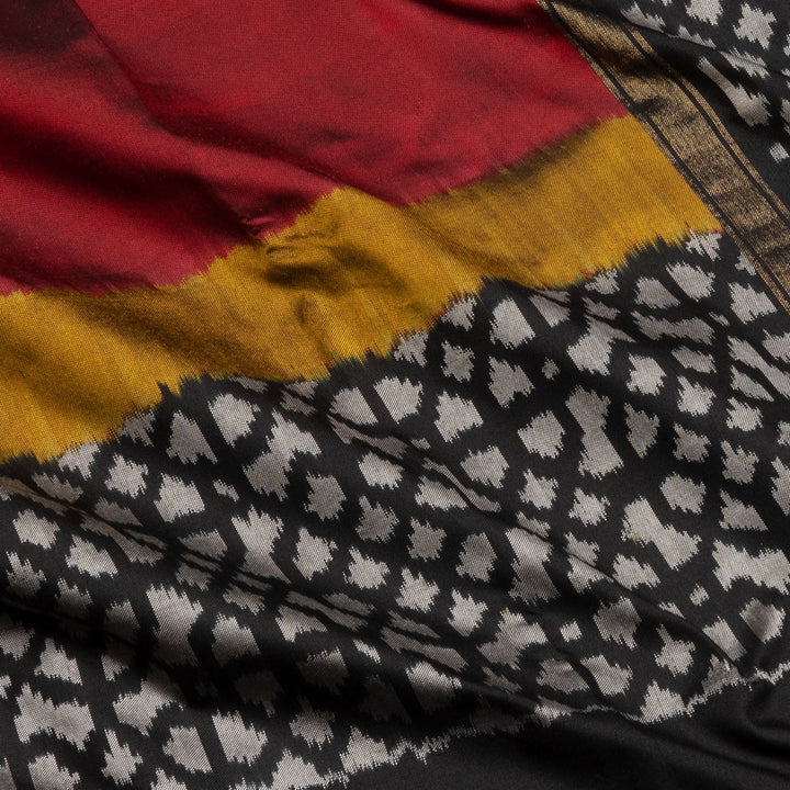 Red Pochampally Ikat silk saree with yellow ikat border, black panel, and black and white ikat pallu, paired with plain black blouse.