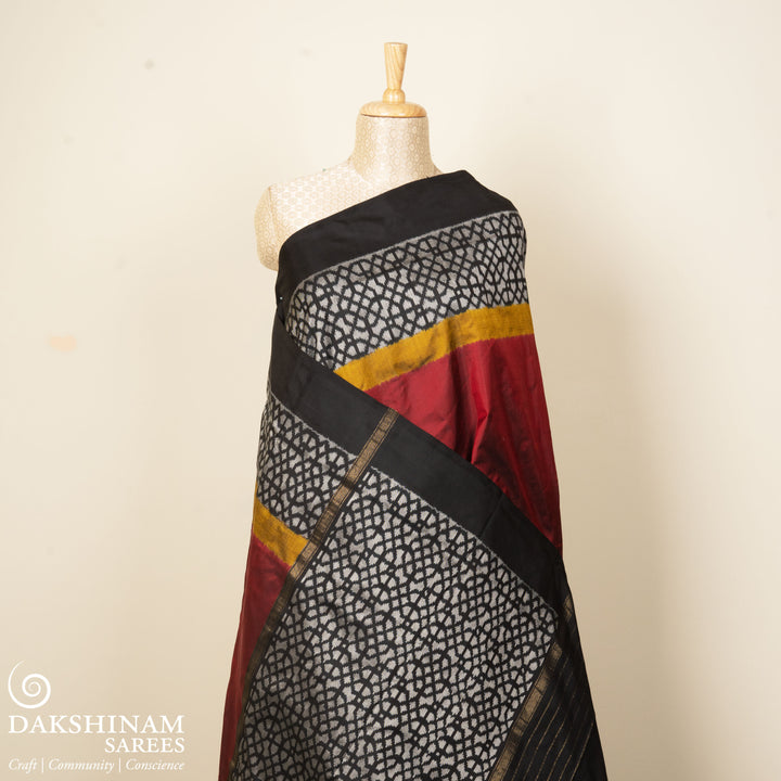 Red Pochampally Ikat silk saree with yellow ikat border, black panel, and black and white ikat pallu, paired with plain black blouse.