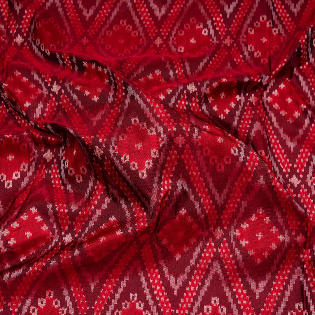 Red Pochampally Ikat silk saree with diamond motifs, red and gold zari border, and temple design pallu with arrow patterns, paired with plain red blouse with zari border.