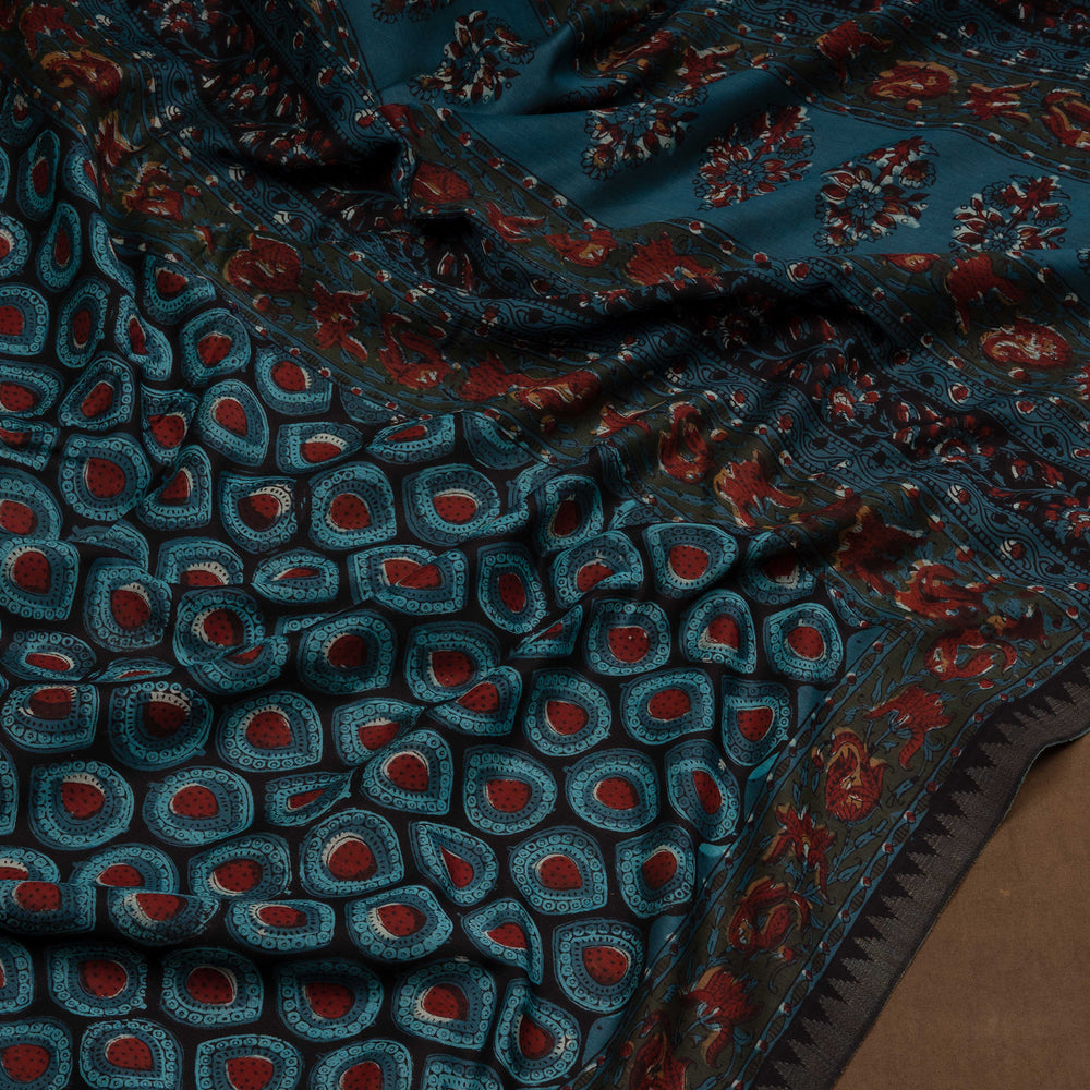 Blue handwoven Chanderi silk saree with Ajrakh print, gicha temple border, floral pallu design, paired with light blue blouse with chevron lines.