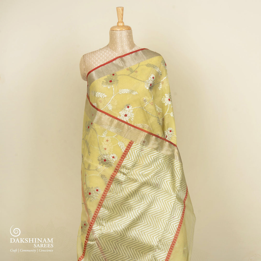 Lime yellow Kota doria silk saree with silver zari floral lines, chevron pallu and panel border with red blouse