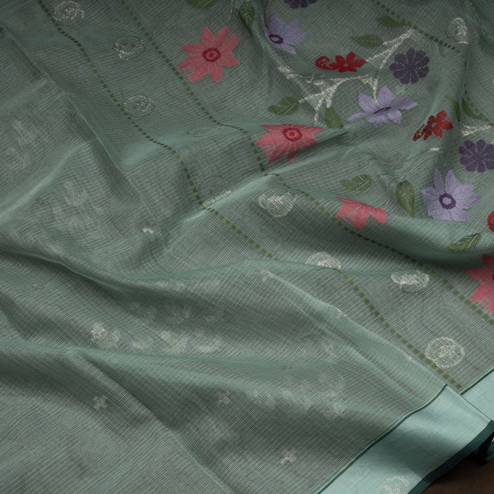 Moss green Kota doria silk saree with silver zari floral motifs, monotone border and pallu with silk thread flowers and chevron blouse