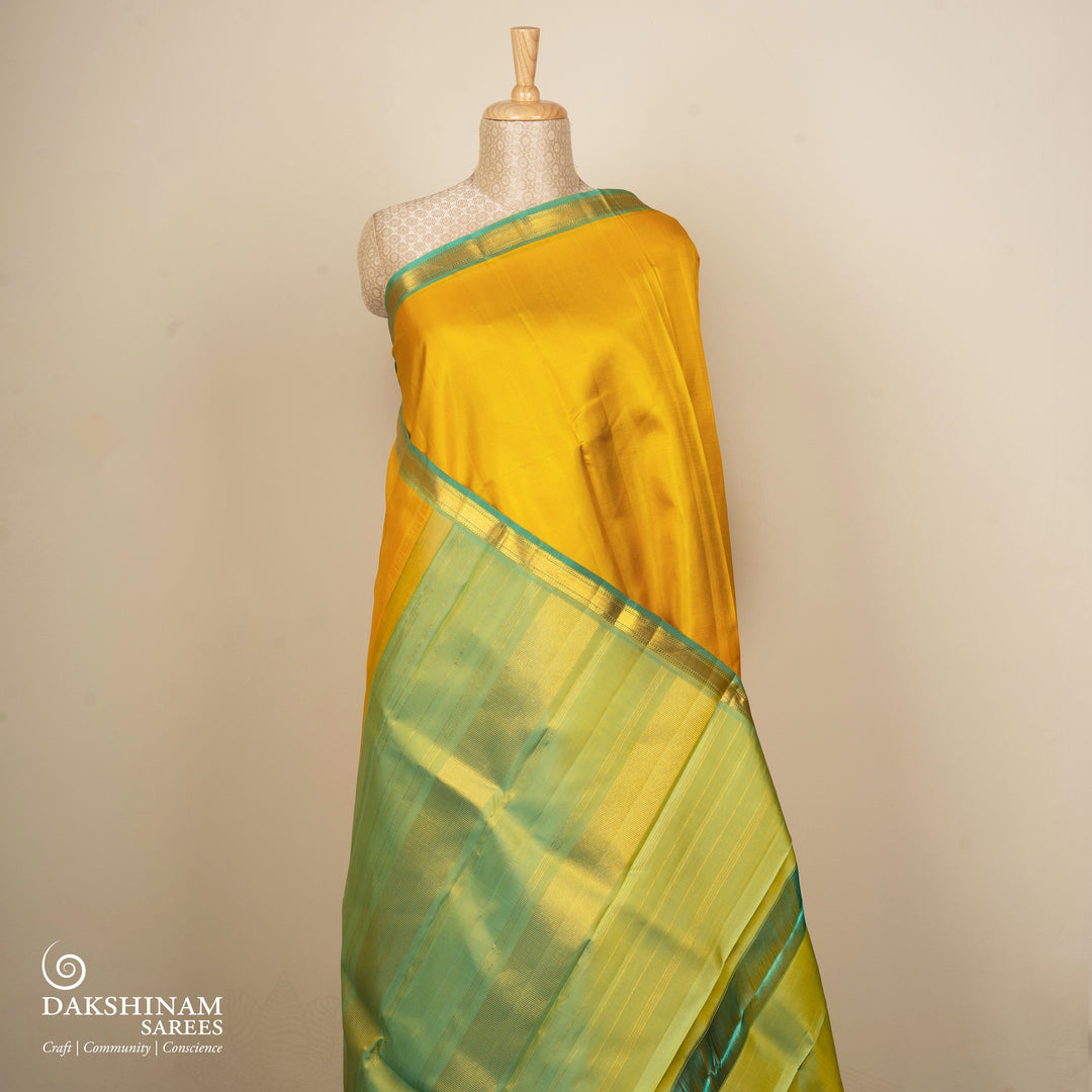 Yellow Kanjivaram silk saree with plain body, aqua blue dual-tone getti border and blue green paneled pallu with matching blouse