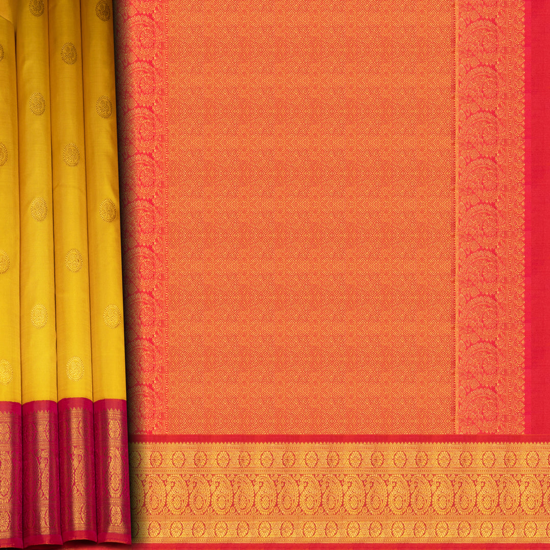 Yellow Kanjivaram silk saree with mayil buttas, pink korvai border featuring chakram and mango motifs, paired with plain pink blouse.