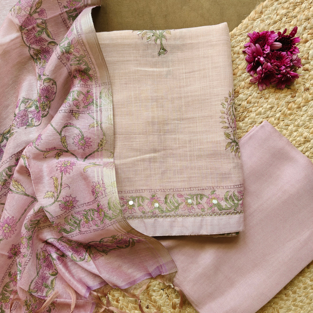 Elegant purple 3-piece suit set featuring floral prints with light orange applique work on tissue fabric. Paired with a plain purple bottom and a floral printed Chanderi silk cotton dupatta for a rich and graceful ethnic look.
