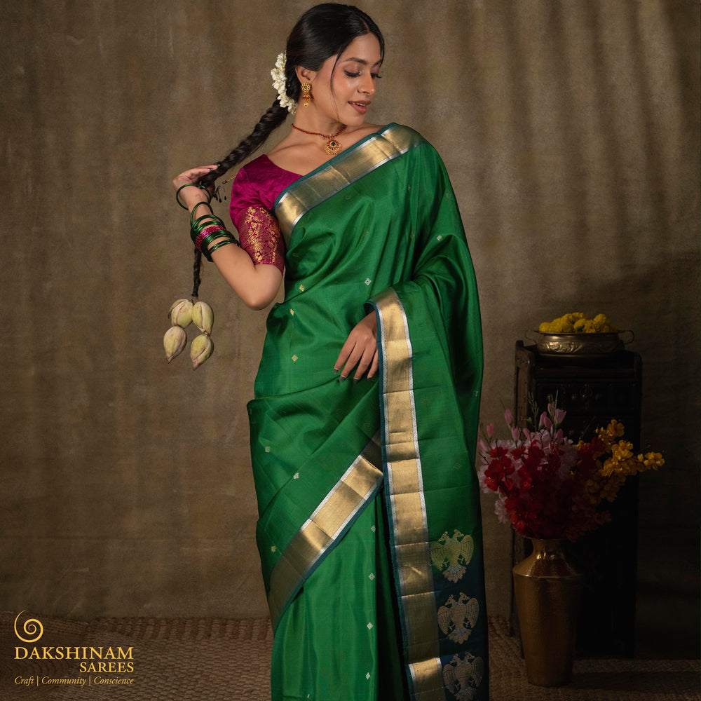Green soft silk saree with small all-over buttas, peacock green border featuring gold zari Bavanchi designs and silver zari chevron edges, Rettaberunda motif pallu and matching blouse.