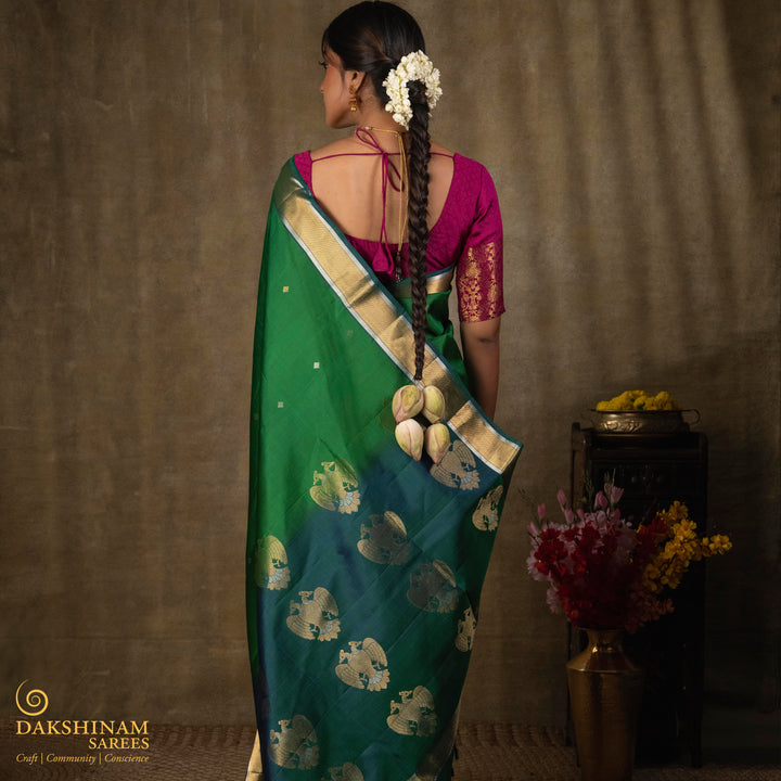 Green soft silk saree with small all-over buttas, peacock green border featuring gold zari Bavanchi designs and silver zari chevron edges, Rettaberunda motif pallu and matching blouse.
