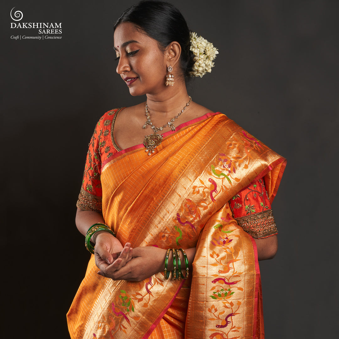 Orange Kanjivaram silk saree with checkered body, Paithani lotus vine and parrot border, pink selvedge and traditional pallu.