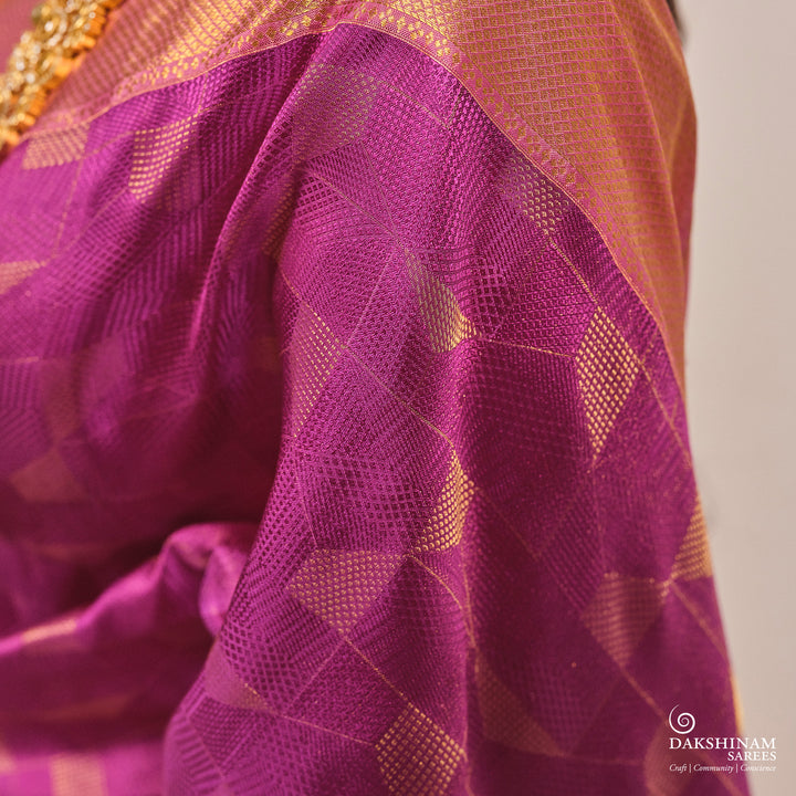 Close-up of a purple and gold saree with a brand logo in the corner.