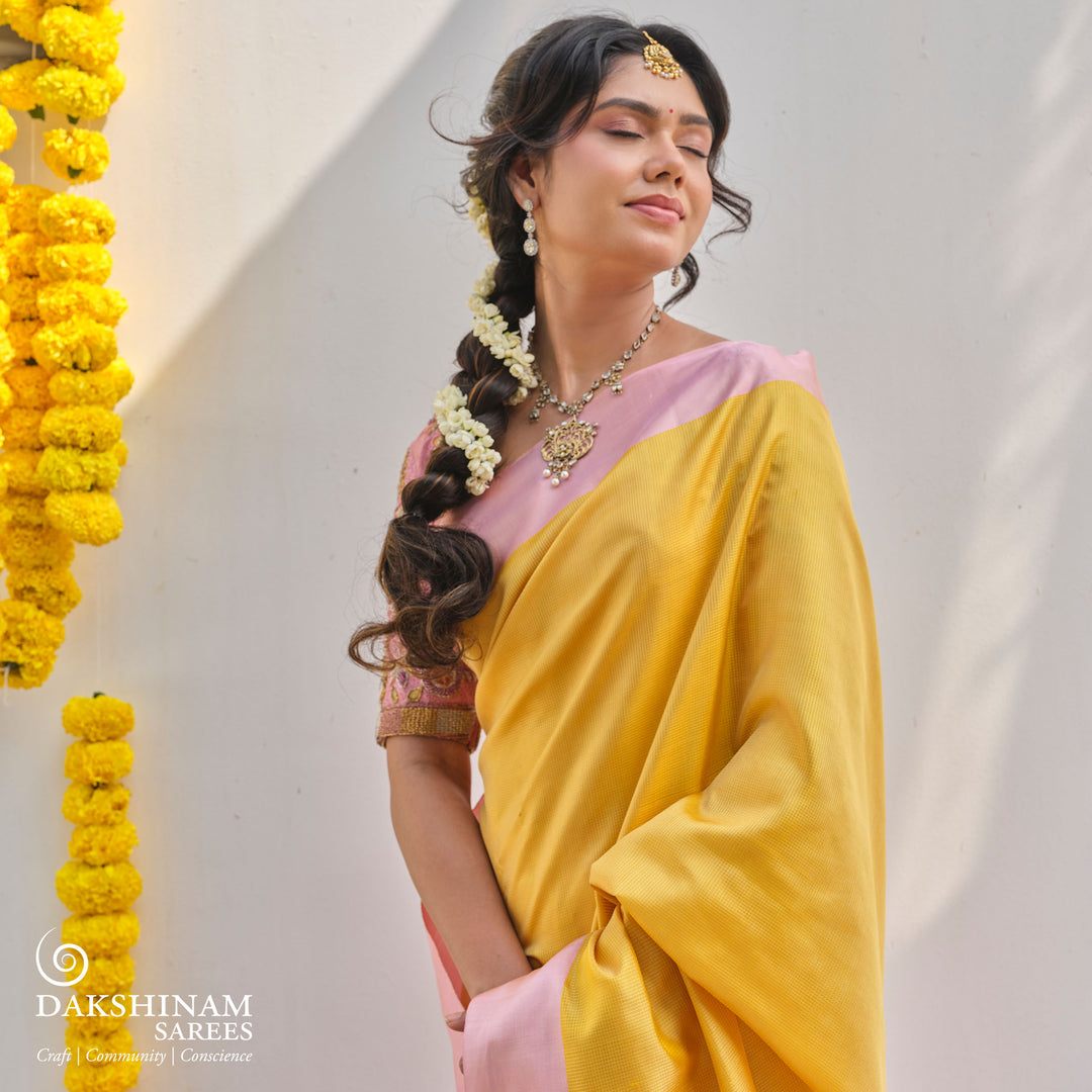 Yellow soft silk saree with self textured body and baby pink pallu with floral vine and lotus zari design