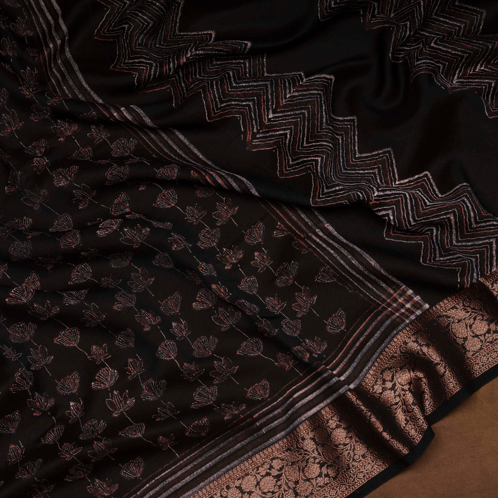 Black Chanderi silk cotton saree with white lotus floral print, gold zari border and orange striped pallu