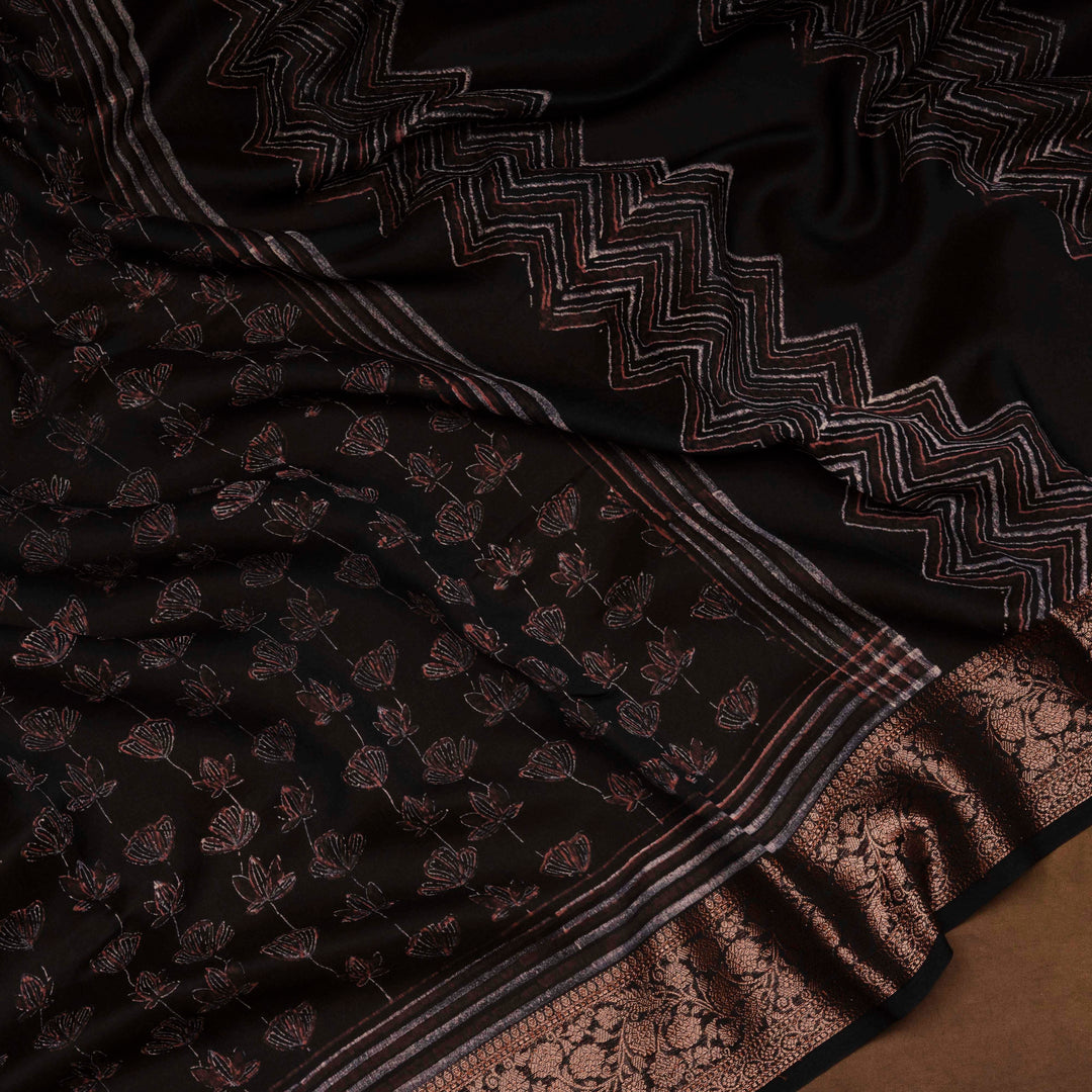 Black Chanderi silk cotton saree with white lotus floral print, gold zari border and orange striped pallu