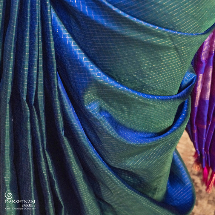Peacock blue Korvai Kanjivaram silk saree with gold zari Vairaoosi checks, magenta contrast border, peacock motifs, diamond panel and striped pallu, paired with magenta blouse.